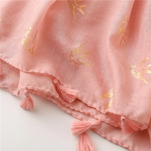Detail of pink cotton linen scarf featuring gold foil swallow prints and fringe edges