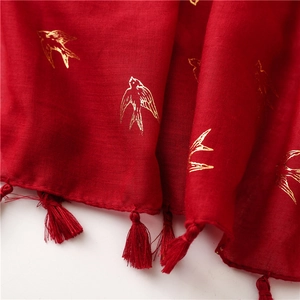Detail of red cotton linen scarf with golden swallow print and fringe tassels