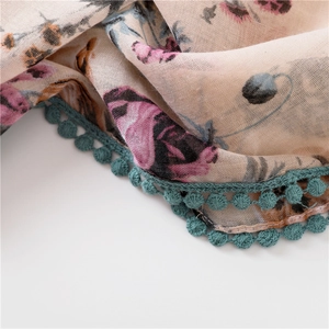 Détail du foulard en coton et lin imprimé floral avec bordure en dentelle pompon turquoise