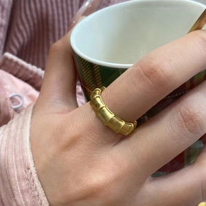 Elegant gold-plated bamboo joint open ring on a finger holding a ceramic coffee cup