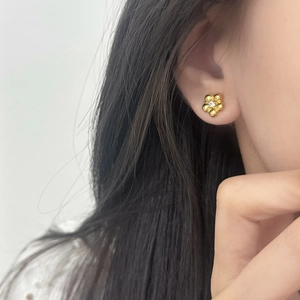 Exquisite gold flower stud earrings with central crystal detail on model's ear