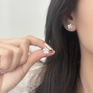 Elegant silver five-petal flower stud earrings with full zircon inlay shown on ear