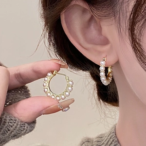 Élégantes créoles dorées avec petites perles blanches sur modèle, style vintage