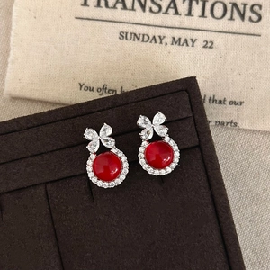Detail of silver bow earrings with red resin cabochon and pavé cubic zirconia