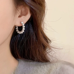 Gros plan de boucles d'oreilles créoles argentées avec perles blanches sur modèle