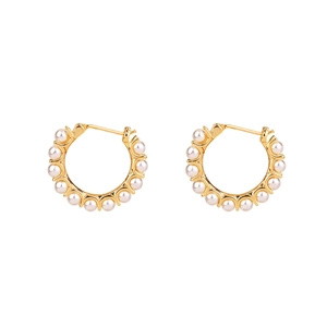 Boucles d'oreilles créoles dorées avec perles blanches sur fond blanc élégant