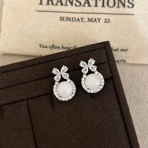 Detail of silver bow earrings with round white opal and sparkling cubic zirconia stones