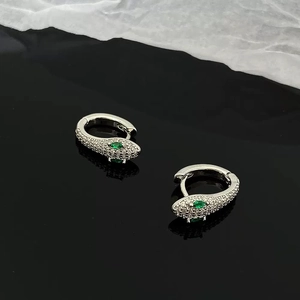 Gros plan détaillé de boucles d'oreilles serpent argentées avec zircons et yeux verts