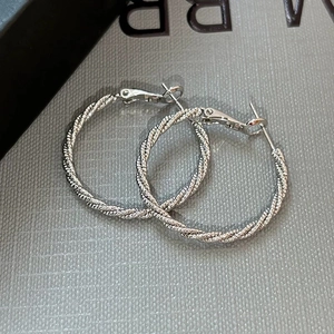 Exaggerated silver twisted hoop earrings with textured metal finish and secure clasp