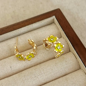 Dettaglio di orecchini a fiore dorati con petali gialli e zirconi in un cofanetto