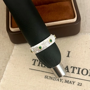 Detailed close-up of retro silver ring with green gemstones and vertical stripe textures