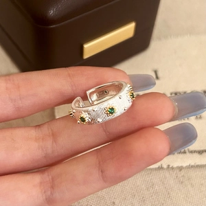 Macro detail of vintage silver brushed ring with gold floral settings and green zircon