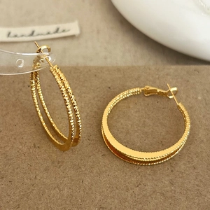 Detailaufnahme goldener Doppel-Creolen mit strukturierter Diamond-Cut-Oberfläche