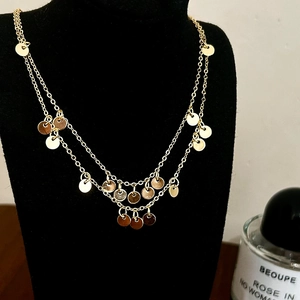 Detail of gold double-layered sequin necklace with polished round pendants on a black stand
