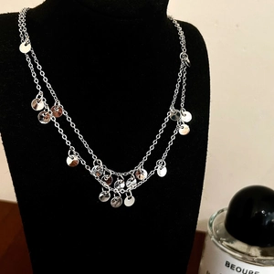 Close-up of double-layered silver necklace with polished round disc pendants on black bust