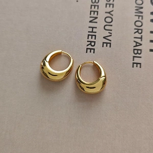 Close-up of chunky gold-plated teardrop hoop earrings with a high-polished metallic finish