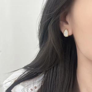 Sparkling teardrop stud earrings in gold finish with crystal inlay on a model's ear