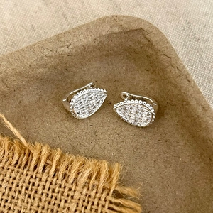 Macro shot of silver teardrop earrings with full pave diamonds on a rustic tray