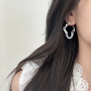 Elegant twisted silver hoops with light blue crystal beads shown on model
