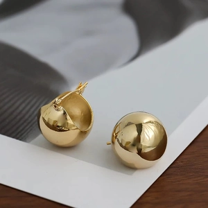 Vue détaillée de boucles d'oreilles boules dorées sur un présentoir artistique