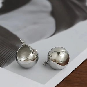 Vue macro de boucles d'oreilles sphériques argentées avec une finition polie miroir chic