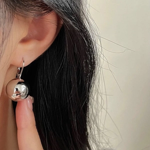 Macro shot of large silver mirror ball earrings showing high reflective metal finish