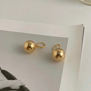 Detailed close-up of gold metal ball earrings with high-polish mirror finish surface