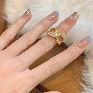 Elegant gold-tone criss-cross zircon ring with brushed finish worn on index finger