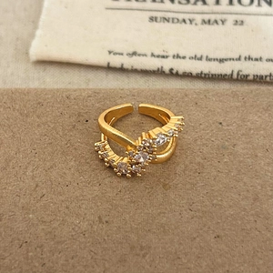Macro detail of gold crossover ring featuring shimmering cubic zirconia on textured surface