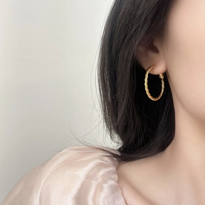 Elegant gold twisted rope hoop earrings worn by a model for a minimalist daily fashion look