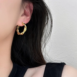 Boucles d'oreilles Mobius dorées de style vintage portées par un mannequin chic