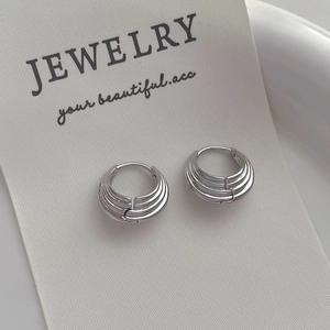 Close-up of silver layered textured hoop earrings on white jewelry display card