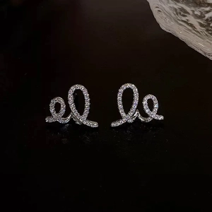 Détail macro de boucles d'oreilles croissant argentées serties de zircons cubiques