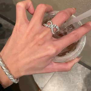 Silver infinity crisscross ring and twisted bangle set with pavé stones on coffee cup