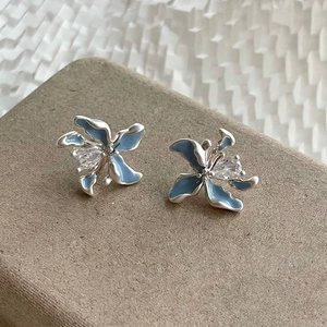 Boucles d'oreilles fleurs en émail bleu et argent avec zircon sur support d'affichage