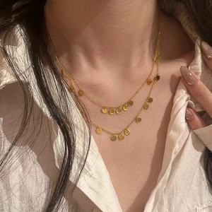 Elegant gold-tone multi-layered necklace with round sequin pendants worn on a model