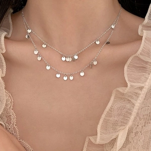 Elegant silver-tone layered necklace with round disc pendants worn on model's neck