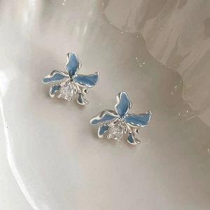 Macro détaillée de boucles d'oreilles orchidée en émail bleu clair avec zircon