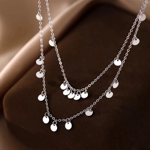 Detail shot of silver double-layered necklace with small round charms on suede box