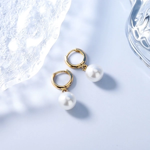 Elegant gold hoop earrings with white round pearl pendants on a light blue background