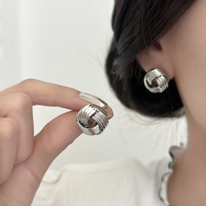 Minimalist silver twist knot stud earrings featuring a polished metallic mirror finish