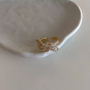 Elegant gold bow open ring with cubic zirconia on minimalist ceramic dish display