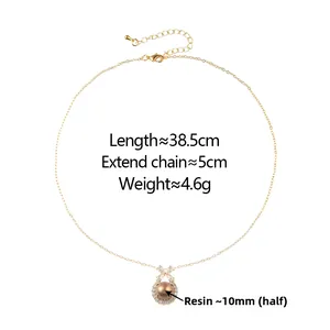 Detail of gold bow necklace with 10mm brown resin bead and sparkling zircon accents