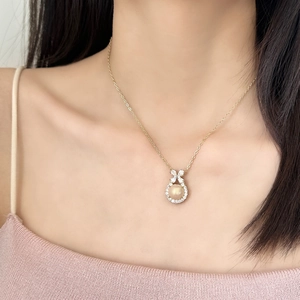 Elegant gold bow necklace with champagne pearl and zircon pendant on model