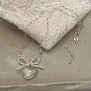 Collier élégant en perles argentées avec nœud en nacre et pendentif cœur cristal