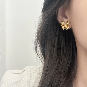 Boucle d'oreille papillon évidée dorée avec oxydes de zirconium sur l'oreille