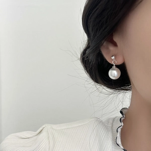 Élégantes boucles d'oreilles perles blanches rondes avec clous argentés sur modèle