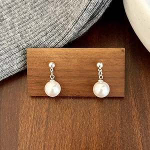 Gros plan détaillé des boucles d'oreilles perles blanches avec tiges en argent
