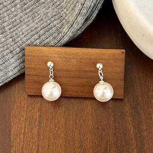 Vue détaillée de boucles d'oreilles perles élégantes sur support en noyer et tricot gris