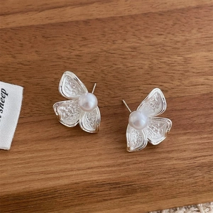 Detailed macro view of silver butterfly pearl earrings with hammered metal texture